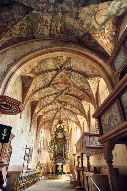 Das mit farbigen Bildwerken an Wänden und Decken reich geschmückte Gotteshaus ist eine wahre Bibel der Armen. Ehemalige Wehrkirche aus dem 16. Jahrhundert.
