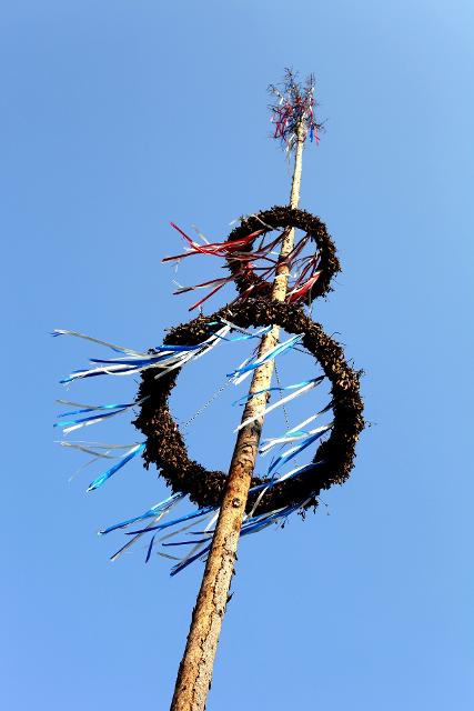 Das Bild zeigt einen Maibaum mit geschmückten Kränzen.