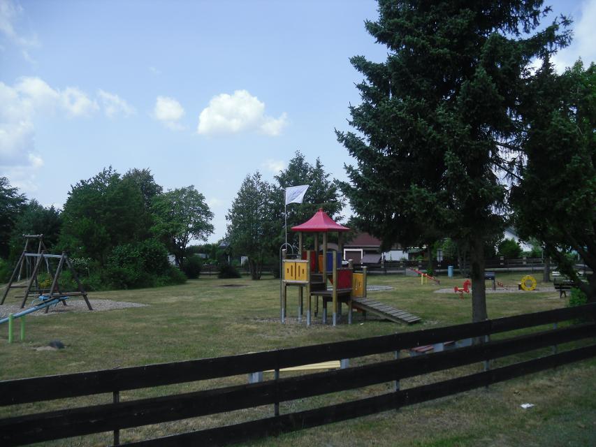 Das Bild zeigt eine Gesamtübersicht des Spielplatzes in Presseck.. Es gibt eine Seilbahn, Kletterturm mit Rutsche, Schaukeln; Sandkasten, Sitzgruppen, Wippe.