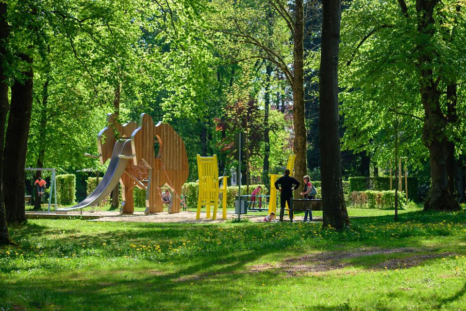 Das Bild zeigt den Spielplatz im Stadtpark in Münchberg. Es gibt ein Klettergerüst, eine Schaukel, Sandkaste, Kletterturm mit Rutsche.