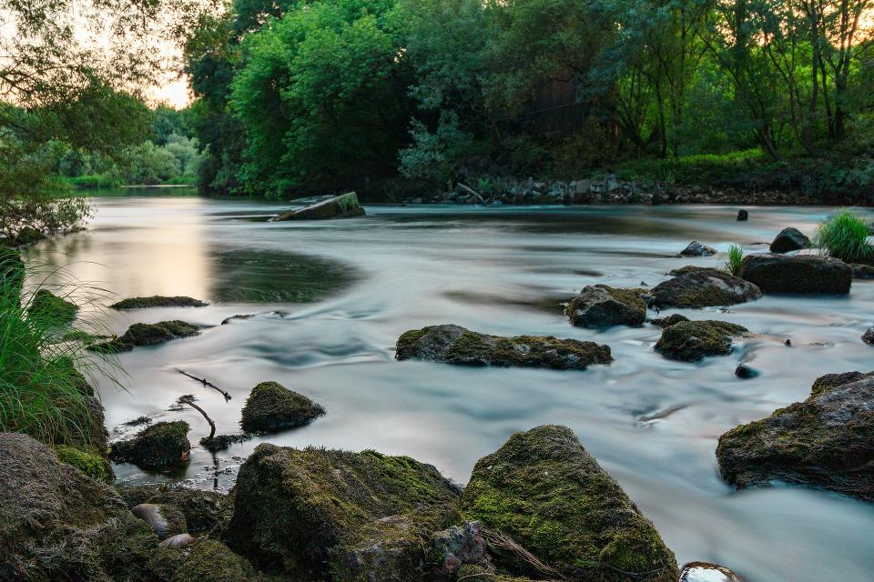 Das Bild zeigt einen Fluß, in dem große, flache Steine liegen.