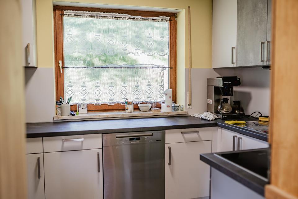Das Bild zeigt die Küche im Wanderheim Marlesreuth. Zu sehen ist eine Küchenzeile mit Herd und Spülmaschine sowie ein Fenster.