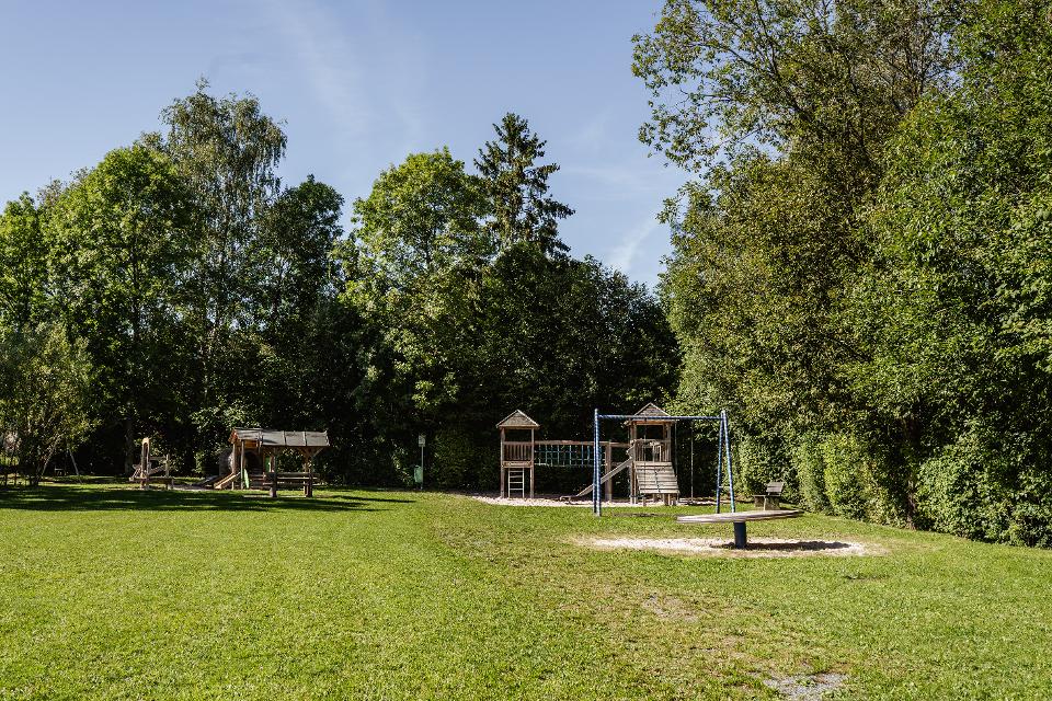 Das Bild zeigt die Freizeitanlage am Wanderheim Marlesreuth. Im Vordergrund ist Rasen zu sehen, im Hintergrund verschiedene Spielgeräte für Kinder.
