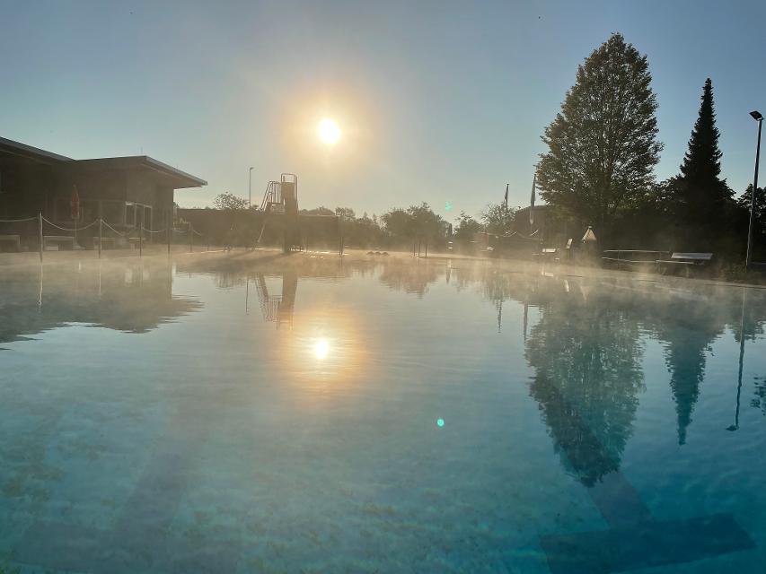 Schwimmbecken draußen mit Nebel und Sonne im Hintergrund