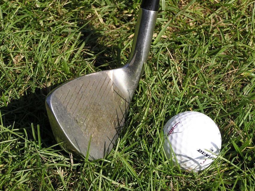 Nahaufnahme von Golfschläger mit Ball aud Rasenfläche