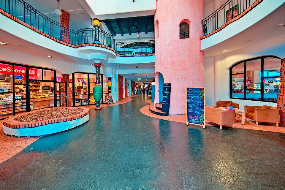 Eingangsbereich des Hundertwasser-Bahnhofs mit Kiosk links und Restaurant rechts