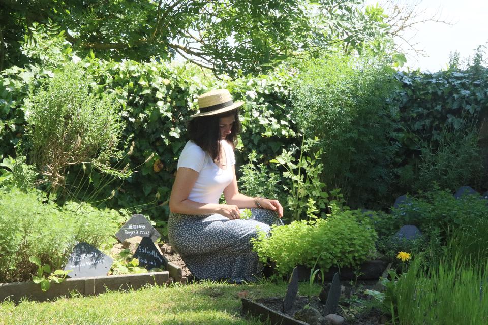 Frau kniet vor einem Beet im Kräutergarten