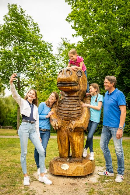 Familie am geschnitzten Holzdrachen macht ein Selfi