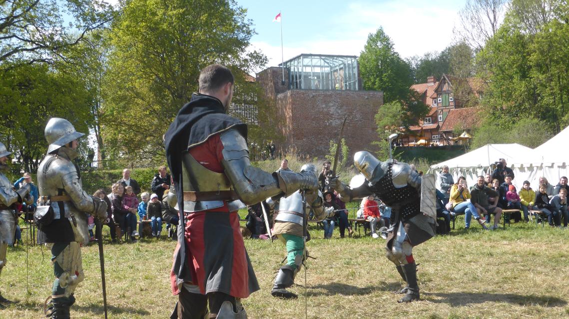 Ritter im Kampf, im Hintergrund die Burg