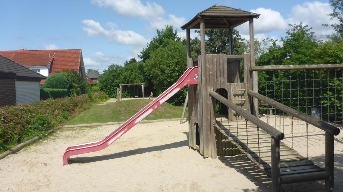 Spielplatz mit Sandfläche, hölzernem Kletterturm, Wackelbrücke, Netz und Rutsche