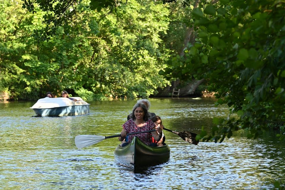 Familie fährt Kanu auf einem Fluss mit grünen Bäumen am Rand