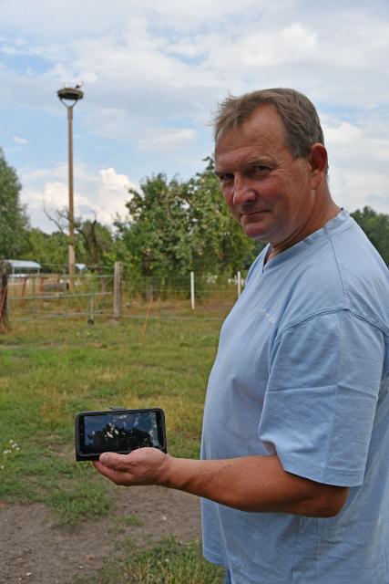 Landwirt Lichte mit Smartphone in der Hand und Storchennest im Hintergrund