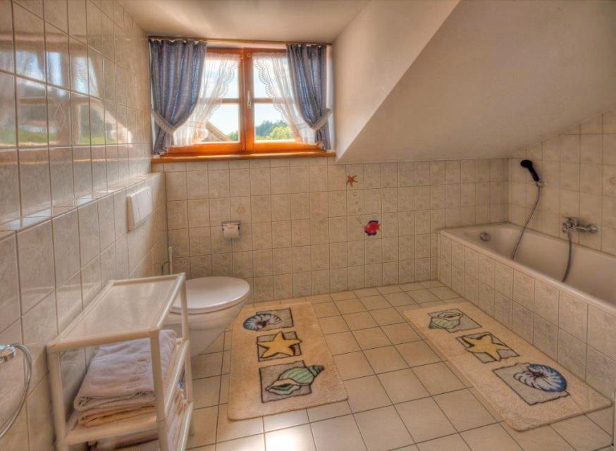 Geräumiges, helles Badezimmer mit WC. Die Badewanne steht unter einer Halbmansarde.
                 title=