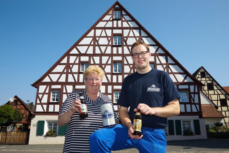 Brauereichefin Sabine Wiethaler-Dorn und ihr Sohn präsentieren Bierspezialitäten vor dem historischen Fachwerkbrauereigasthof