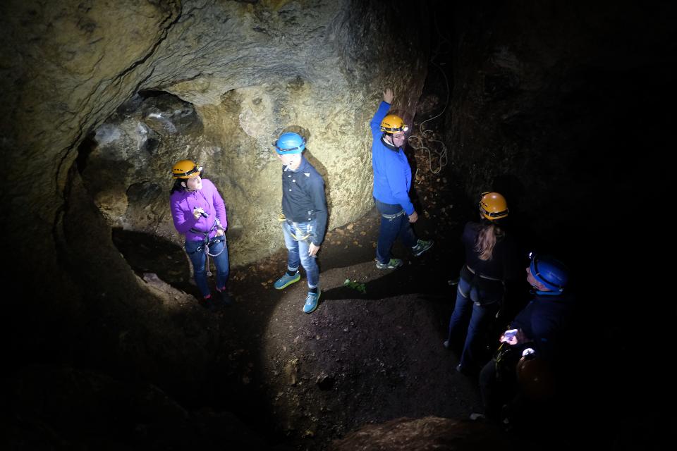 Gruppe mit Kletterausrüstung, Helmen und Stirnlampen in einer kleinen Höhlenhalle