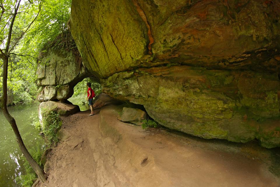 Sandstein-Felsüberhang und Durchlass direkt am kleinen Fluss Schwarzach. Person steht am Durchlass