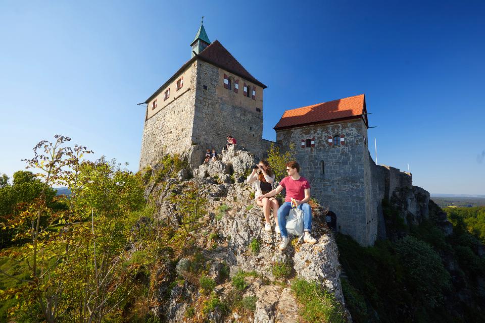 Paar, das auf einem Felsen unterhalb der Burg Hohenstein sitzt