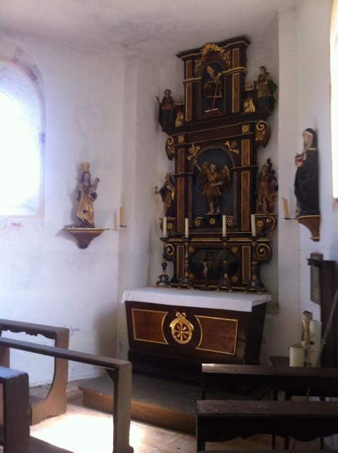 In einer kleinen Kapelle befindet sich ein dunkler hölzerner Altar aus der Spätgotik.