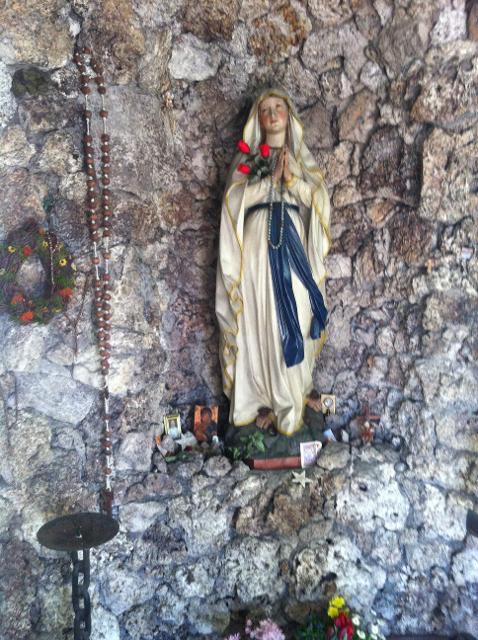 Der Betrachter sieht die Madonna welche in der Lourdeskapelle an der Wand steht.