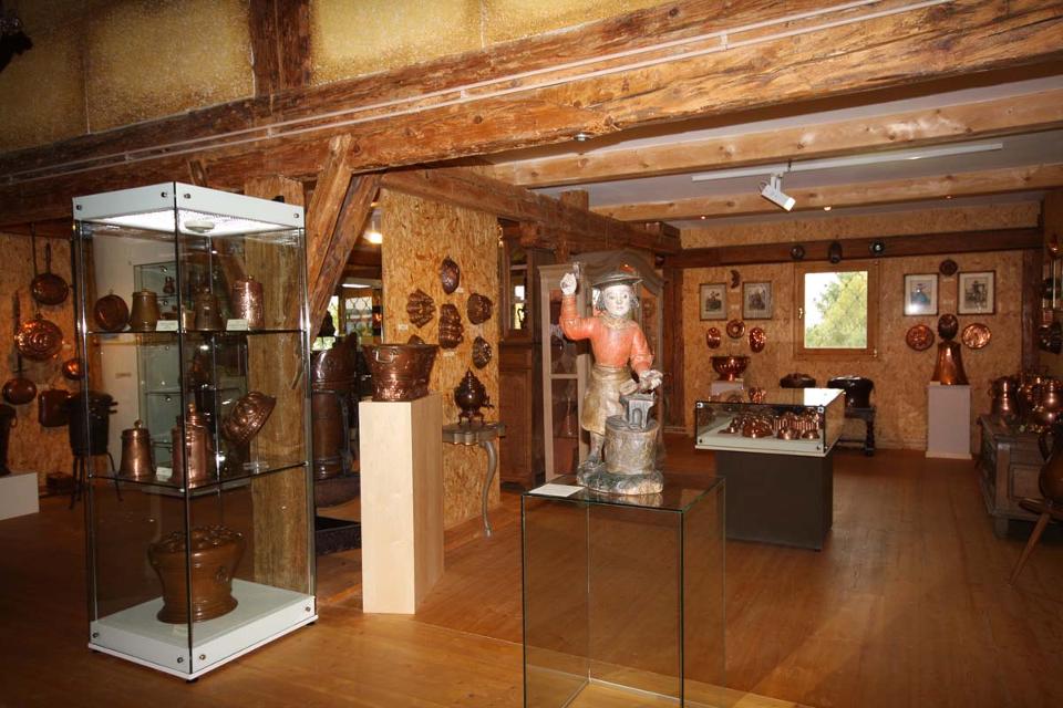Der Betrachter befindet sich im Museum wo viele Vitrinen stehen mit Kupfergegenständen.