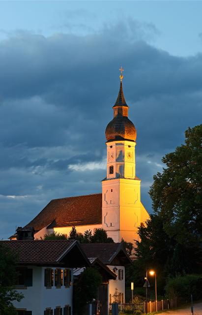 Der Betrachter blickt in der Abenddämmerung auf die beleuchtete barocke Kirche.