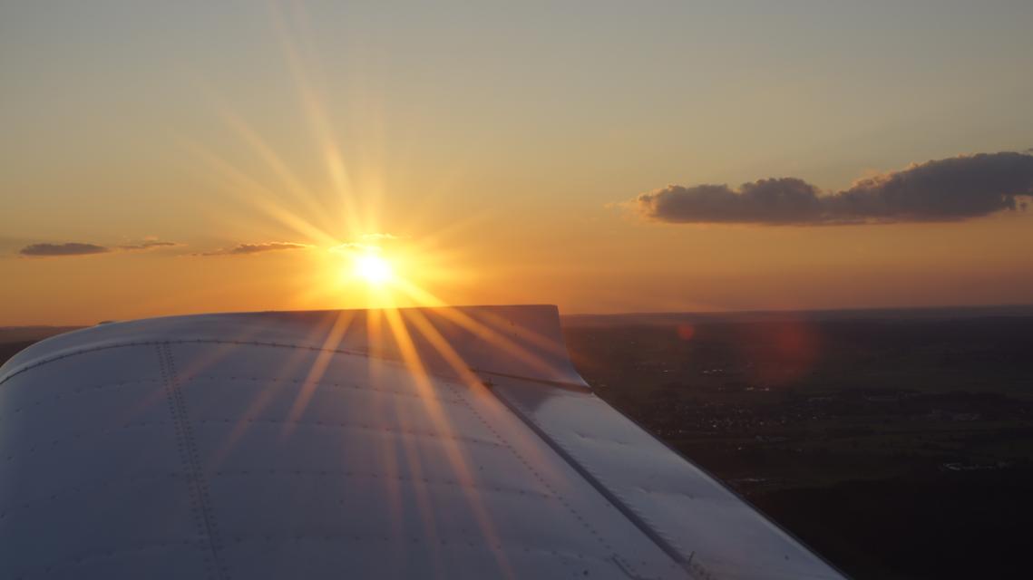 Der Betrachter blickt vom Flugzeug aus in hohen Lüften auf den herrlichen Sonnenuntergang.