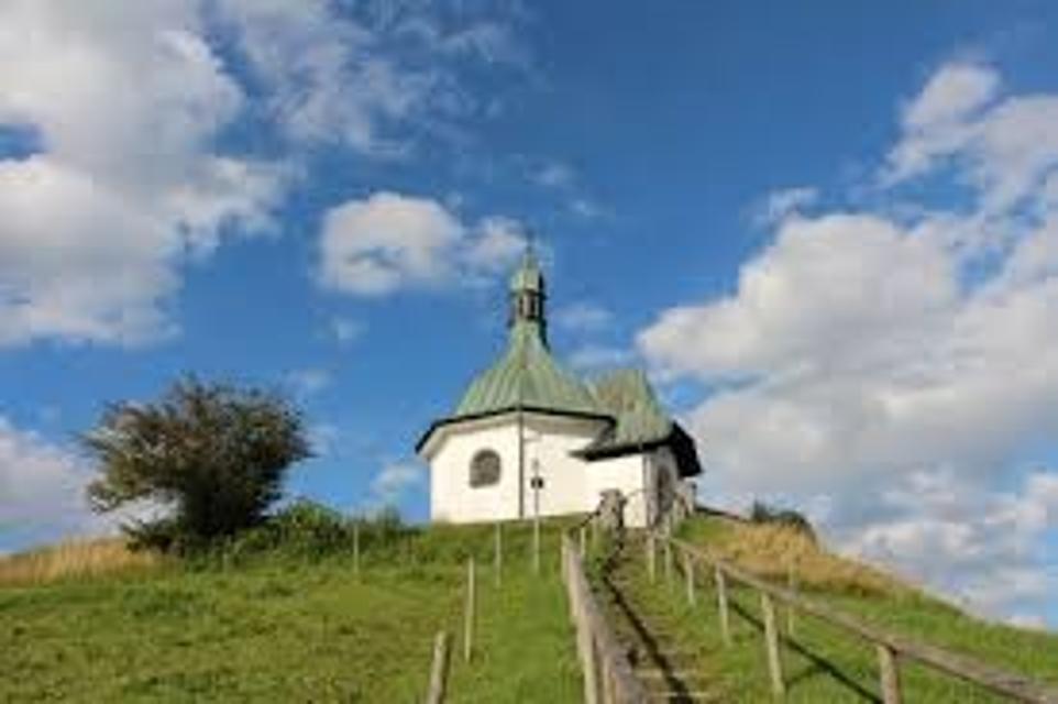 Der Besucher blickt vor sich auf die Stufen dich hoch zu dem Hügel führen auf dem die Kapelle steht.
