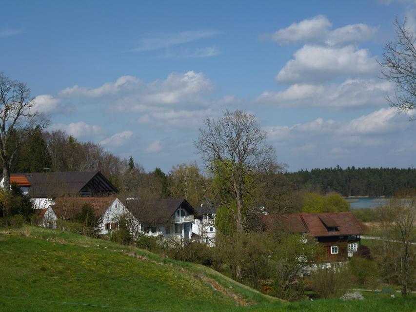 Der Betrachter blickt über einen Hügel und sieht hinter Bäumen Häuser die zur Privatklinik Lauterbacher Mühle gehören.