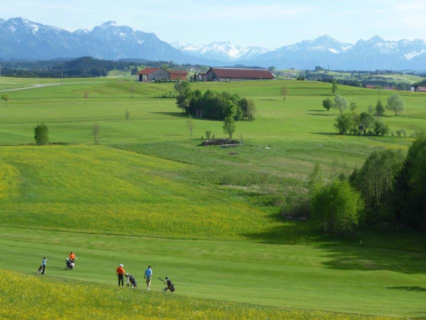 Golfer spielen auf der Anlage. Im Hintergrund herrliches Alpenpanorama.