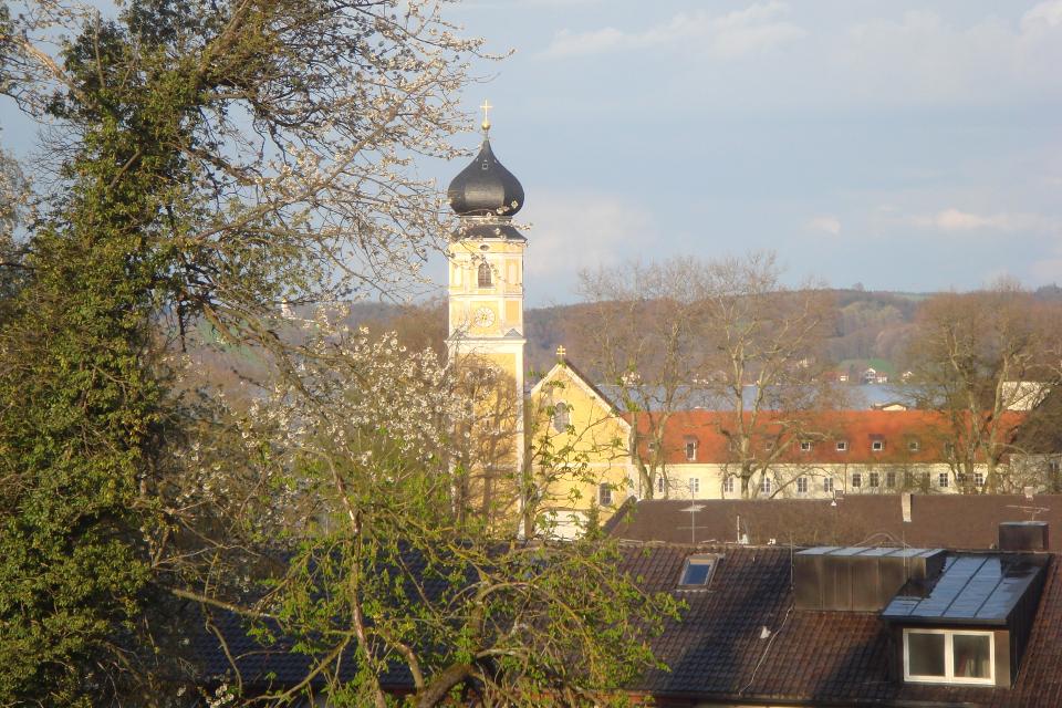 Blick über die Hausdächer Bernrieds hinweg auf die Kirche mit ihrer barocken Kirchturmspitze.