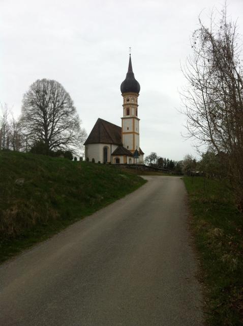 Der Blick verläuft mit der Landstraße direkt auf eine große Kirche.