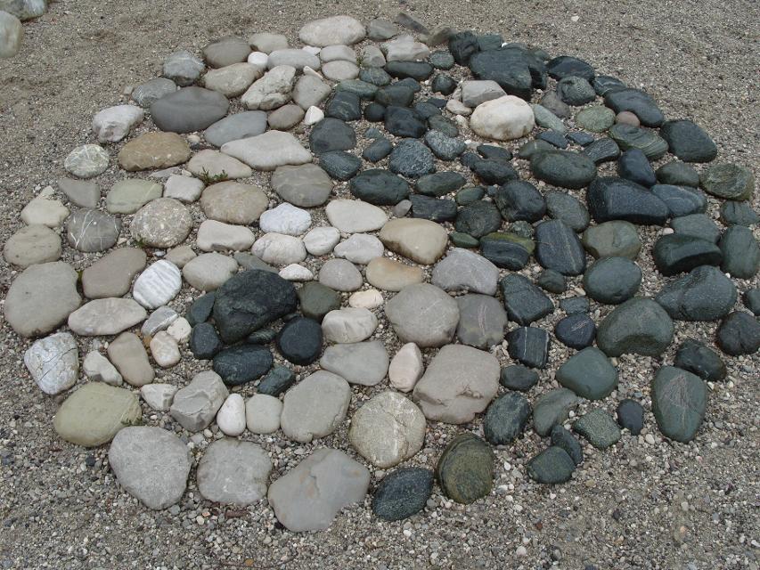 Der Betrachter blickt auf einen kunstvollen Steinkreis am Boden welcher ein Ying-Yang darstellt.