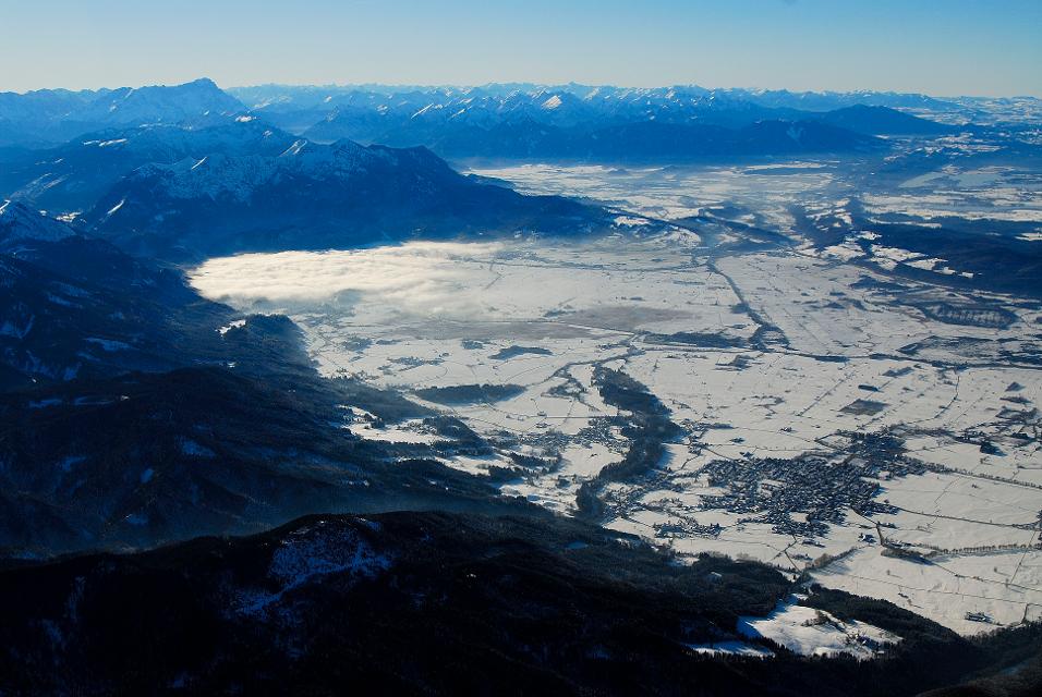Der Betrachter blickt vom Himmel herunter auf die Alpen im Winterkleid.