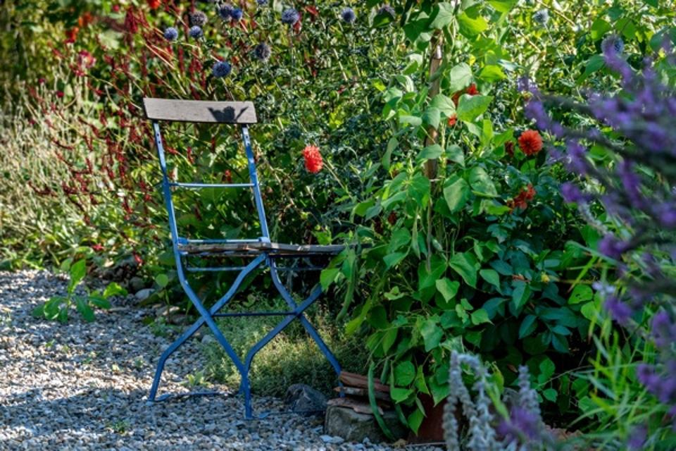 Der Besucher blickt auf einen Stuhl im liebevoll angelegten Garten