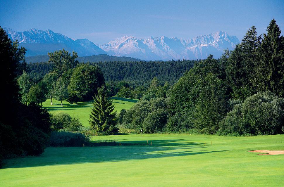 Golfplatz mit vielen Bäumen und herrlichem Alpenpanorama.