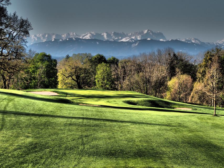 Golfplatz mit Alpenpanorama am Horizont.
