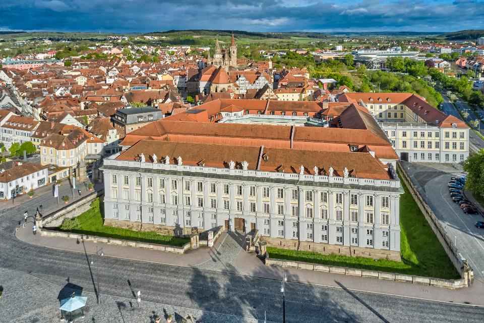 Die Markgräfliche Residenz in Ansbach beeindruckt mit 27 Prunkräumen, inklusive Spiegel- und Kachelsaal sowie einen doppelgeschossigen Festsaal.
                 title=
