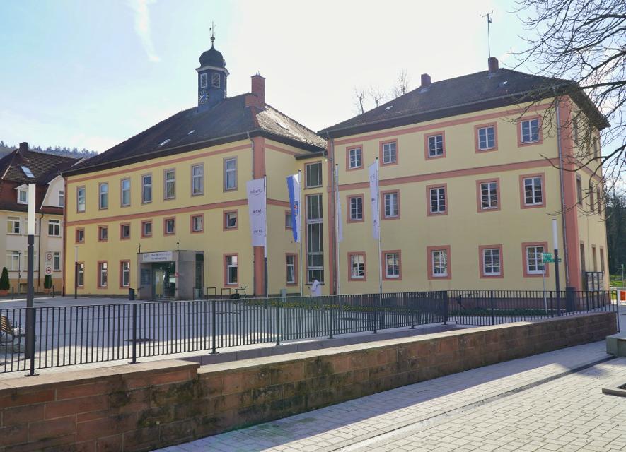 Außenansicht der Tourist-Information in Bad Orb in einem gelb-roten Gebäude, im Vordergrund ein geplfasteter Platz