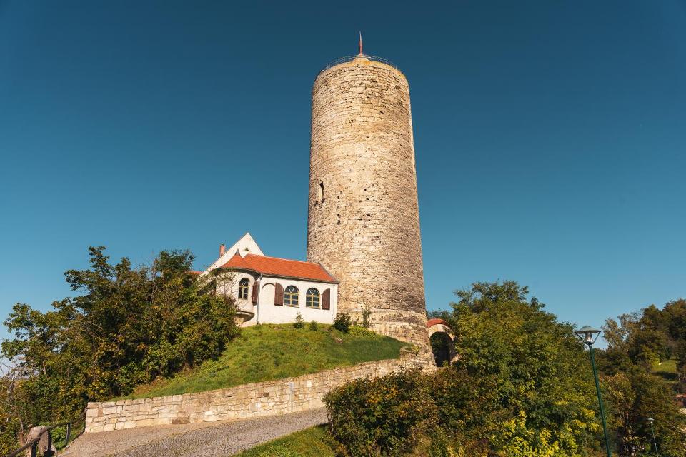 Von den ursprünglichen Anlagen sind noch der 37 m hohe Bergfried und Reste der Umfassungsmauer erhalten. Von der Turmspitze hat man einen fantastischen Blick über das Saaletal.
Im unteren Teil des Bergfrieds kann man die Umsetzung einer einzigarti...